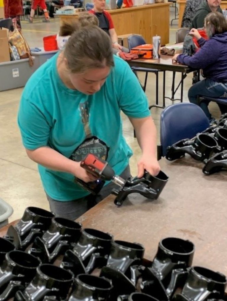 Individual who is working with a drill on a part assembly