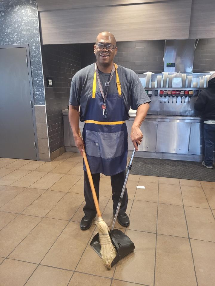 man working at fast food restaurant sweeping
